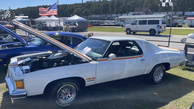 Sunday, May 3, 2026, Carteret County Speedway near Swansboro, NC.  Pictured is a 1977 Pontiac LeMans Can Am in Cameo White with its signature colorful decals and T/A 6.6 shaker hood parked on the speedway’s infield.