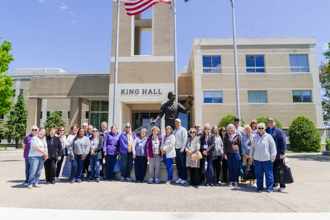 Alums pose for a photo outside of King Hall while on a tour.