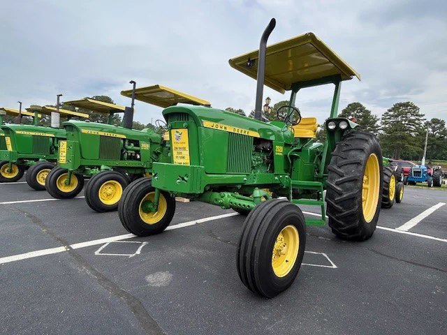 Four John Deere tractors lined up in a parking lot. 