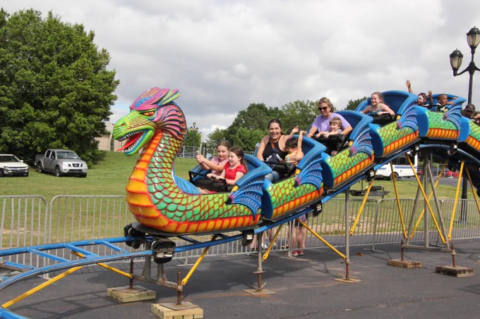 A dragon roller coaster full of people with their hands in the air. 