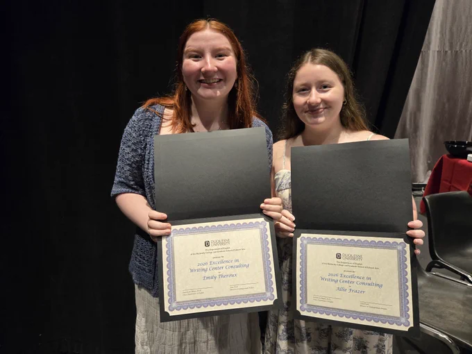 Allison and Emily are standing and holding their award certificates.