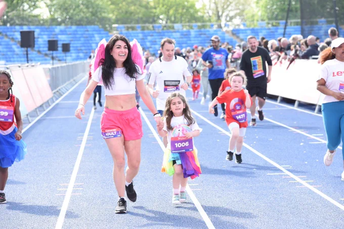 Woman with pink fairy wings and a young girl holding hands during the junior Great Birmingham Run