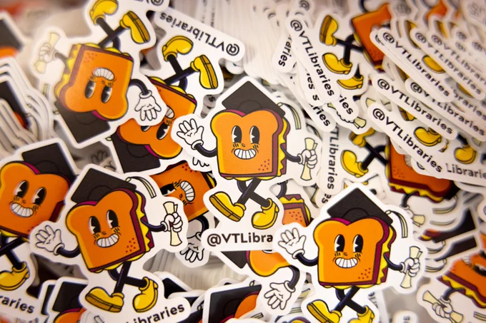 A pile of exclusive Cheesy Nights stickers for Hokie graduates. Sticker features a grilled cheese guy wearing a graduation cap and holding his diploma. 
