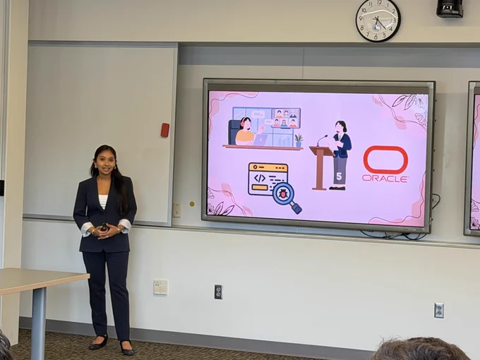 Woman standing in front of a large display screen showing cartoon characters, clocks, and other icons.