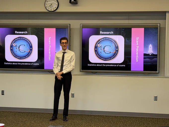 A man standing in front of two large projected displays showing research-related graphics and text.