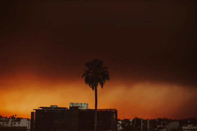 A photograph of the California sky colored during a wildfire. The sun is obscured, and the entire horizon glows deep red-orange, showing what the "Drought Generation" has grown up seeing as normal.