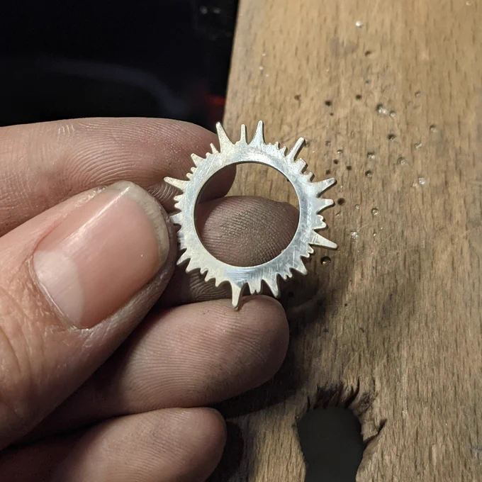 A handheld sterling silver eclipse pendant in progress.