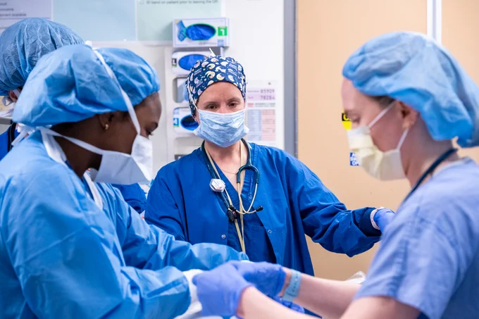 A group of medical professionals wearing scrubs standing together in a clinical setting.