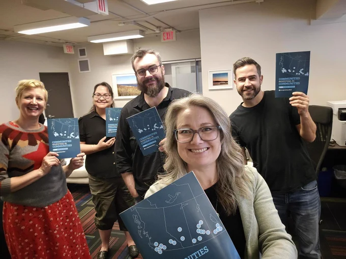 A selfie of members of the Co-operatives First team - three women and two men - holding copies of the 2025 annual report, a document with a dark blue cover and a map of western Canada.
