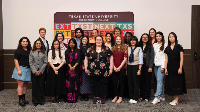 Group photo of graduate students standing in front of a Texas State University Graduate College backdrop.