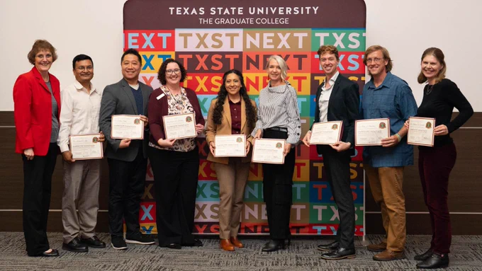 Eight faculty members stand in front of a Texas State University Graduate College backdrop holding certificates of achievement.
