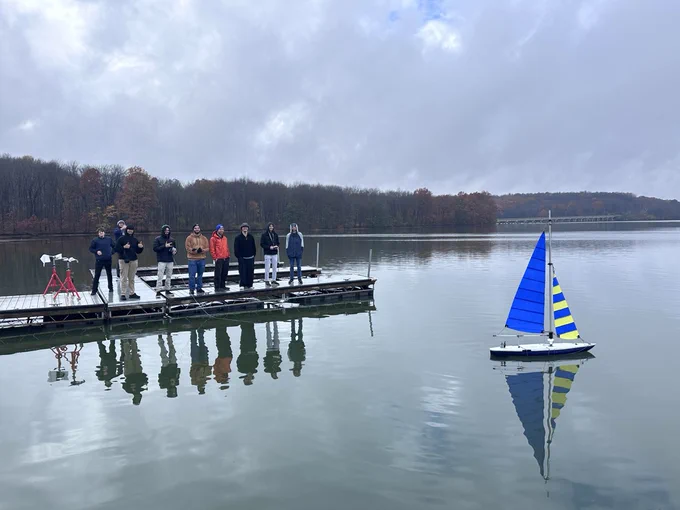 Members of Pitt SailBot on a dock testing their sailbot, the Dan Marina, on Lake Arthur