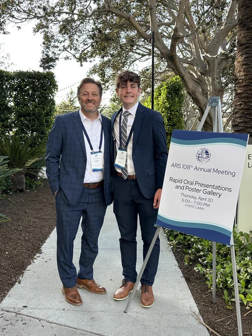 Dr. Jared Robbins and Camden Robbins pose with an ARS Annual Meeting sign
