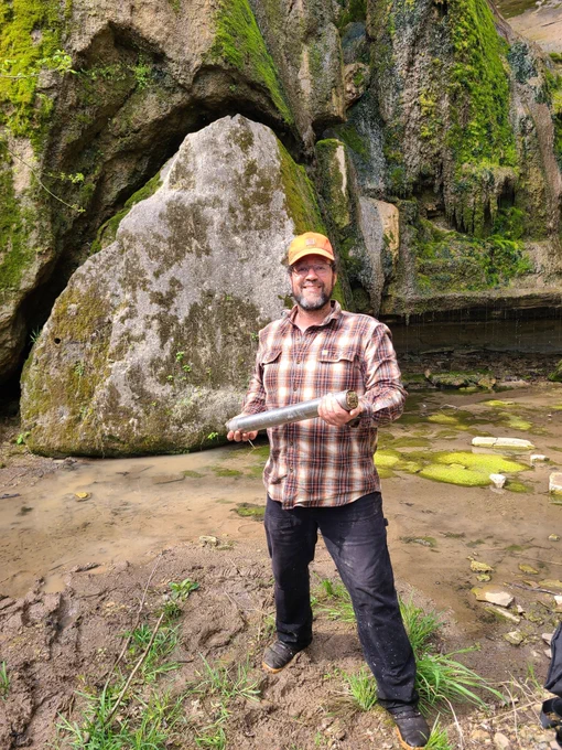 Photo. Jason Dortch holding a core sample in front of a rocky background at Floracliff Nature Sanctuary.