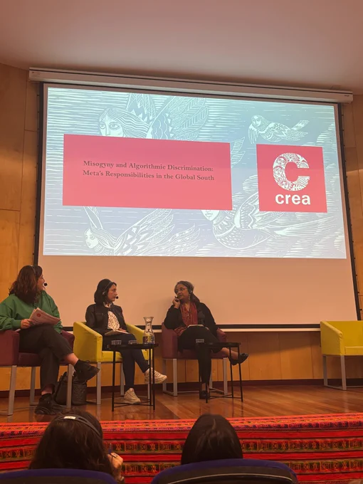 Panel discussion with three speakers seated on stage, wearing headsets, with a projected slide behind them, during a session titled “Misogyny and Algorithmic Discrimination: Meta’s Responsibilities in the Global South”; CREA’s Priya Das, Director – Programs and Innovation, is among the panelists.