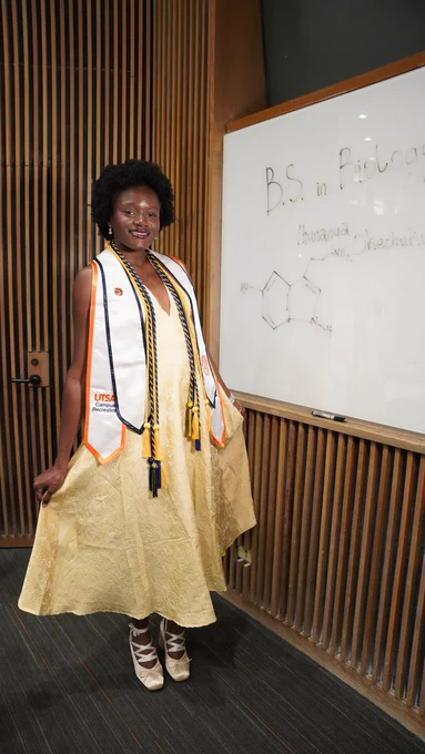 Ihunanya standing in a yellow dress with stoles and chords on her neck, smiling.