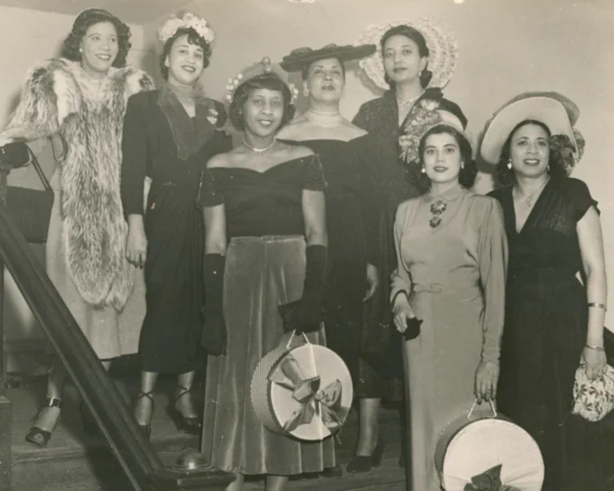 A black-and-white photograph of seven women standing on an a flight of stairs.