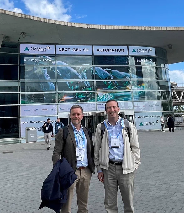 Jordi Jiménez and Pere‑Andreu Ubach from CIMNE standing outside the Advanced Factories 2026 venue, with event banners and robotic‑automation visuals displayed on the convention center entrance.