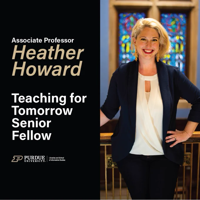 Heather standing in Purdue Union in front of the stained glass windows in a black suit and white top.