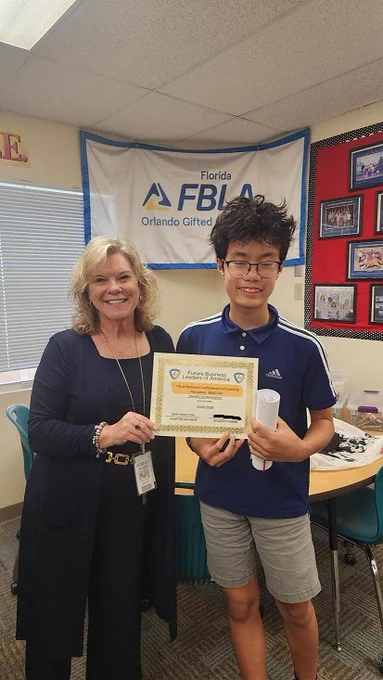 A smiling woman stands next to a young man, both holding a certificate.