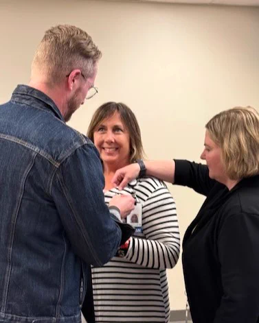 Two people pin a medal on another person who is smiling.