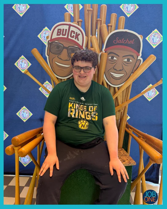 Gage is sitting on a baseball bat throne at the NLBM.