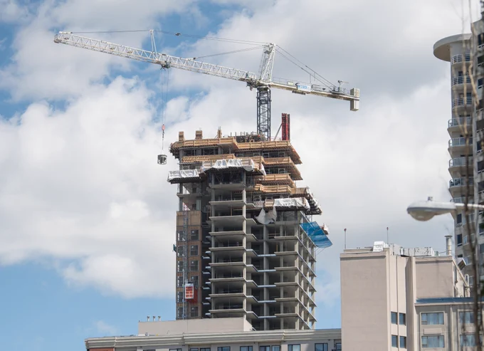 A downtown high-rise apartment building under construction with a crane in the background. 