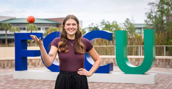 a photo of a student tossing an apple in the air for a photo