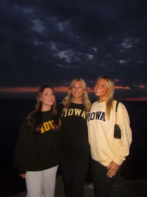Three students at in Iowa gear at sunset.
