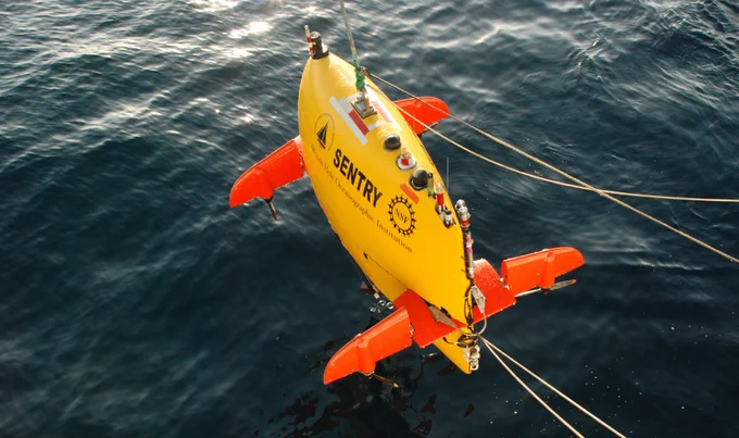 Autonomous underwater vehicle Sentry: Image courtesy of DEEP SEARCH 2017, NOAA-OER/BOEM/USGS.

The yellow and orange autonomous underwater vehicle Sentry being lowered by a cable into the ocean.
