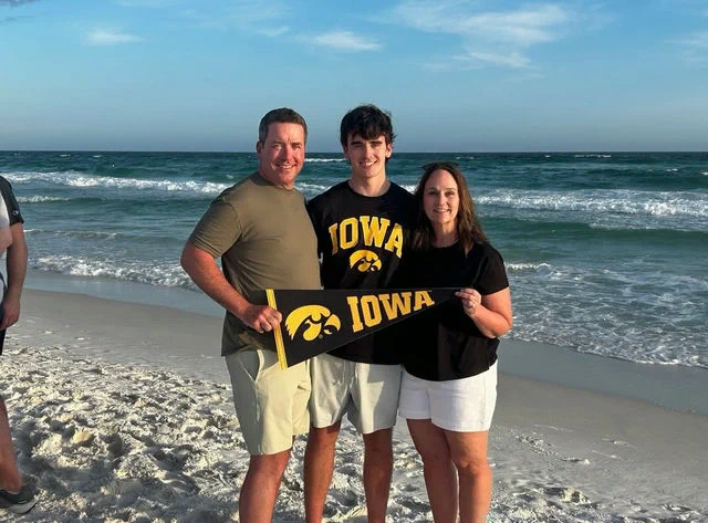 A student with parents holding an Iowa pennant.
