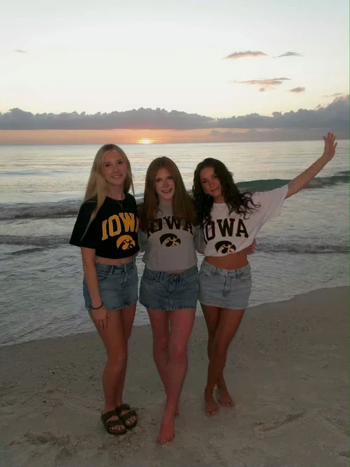 Three students at in Iowa gear at sunset.
