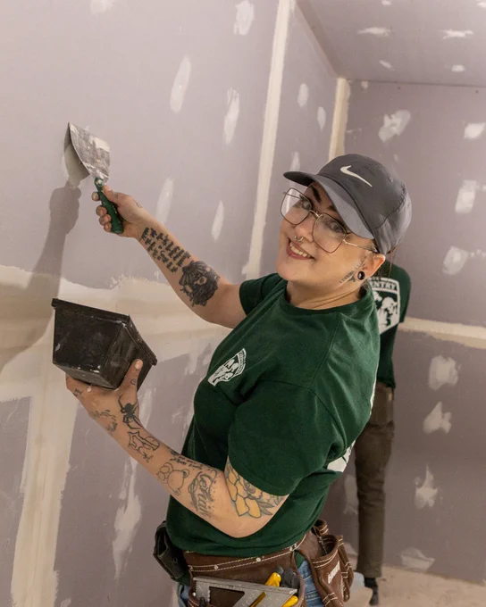 A person using a trowel to apply joint compound on a drywall. 