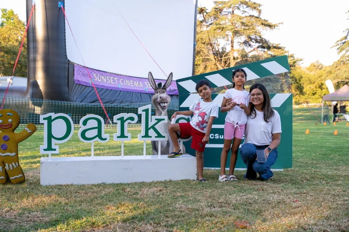 A family posing in front of OC Parks sign.
