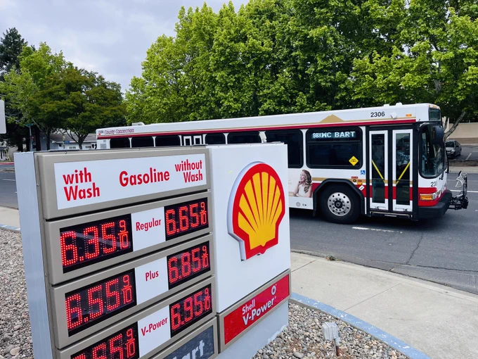 Image of a County Connection bus driving past a gas station displaying gas prices from $6.65-6.95 a gallon (in May 2026).