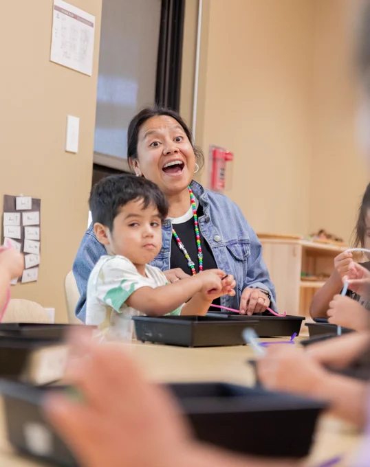A teacher engaging in a conversation with students in a classroom.
