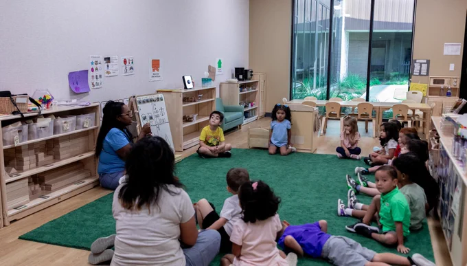 A class sitting in a circle on a rug.

