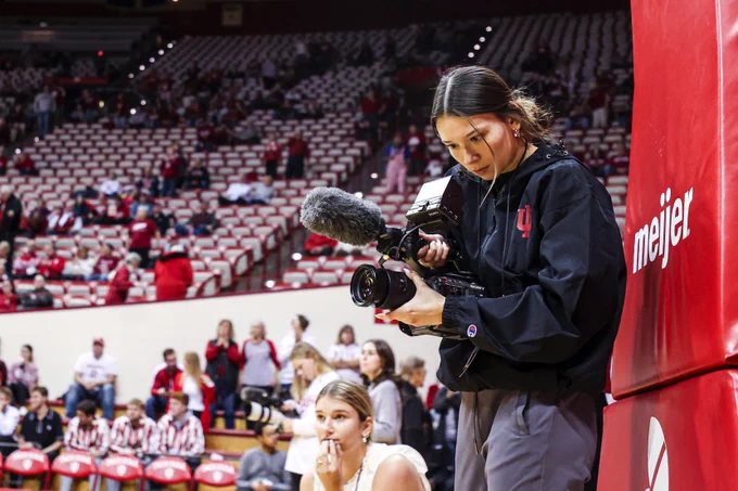 A person films in a basketball arena.