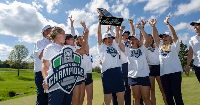 A group of Kent State women's golf athletes on a golf course celebrate winning the MAC Women's Golf Championship. They are wearing matching uniforms and hats, holding a banner and a trophy, with joyful expressions. The background features a clear blue sky and green landscape.