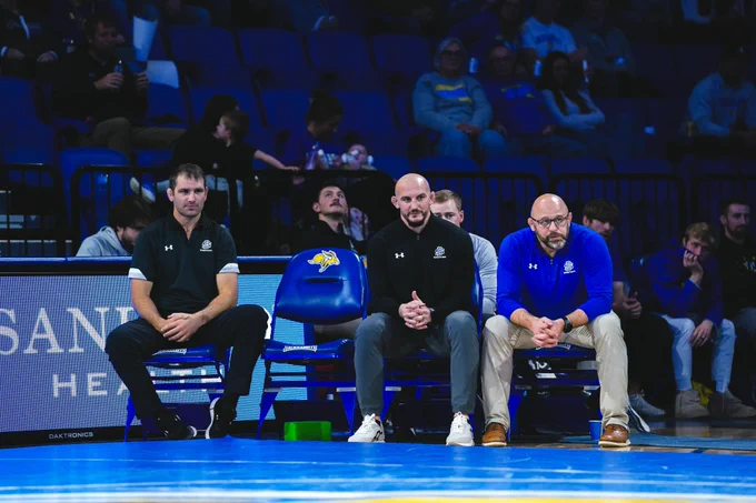 Three Coaches sit during a dual. 