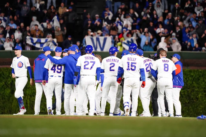 The Cubs celebrate a walk-off win Wednesday night at Wrigley Field. W flags fly in the bleachers as fans celebrate in the background. (Photo: Kyle Sheridan/Major League Baseball)