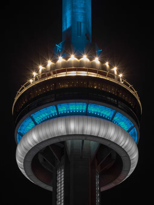 Closeup of the CN Tower at night lit blue, white and grey / Gros plan de la Tour CN illuminée en bleu, blanc et gris la nuit 