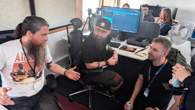Two very beardy gentlemen talk excitedly with representatives from Rare Ltd. while experimenting with Custom Seas.