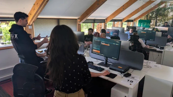A room full of screens running Sea of Thieves' upcoming Custom Seas mode. A member of Flix Interactive gives the thumbs up to the room after presumably relaying some very exciting information.