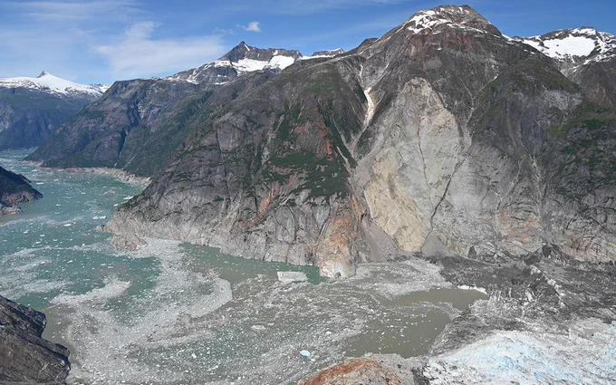 Oblique aerial photo of the 10 August 2025 landslide taken from across the fjord during a U.S. Geological Survey field reconnaissance overflight on 13 August, 2025. Note the trimline along the far side of the fjord, caused by the tsunami stripping the walls of vegetations. View direction is approximately north. Photo by Cyrus Read/U.S. Geological Survey.