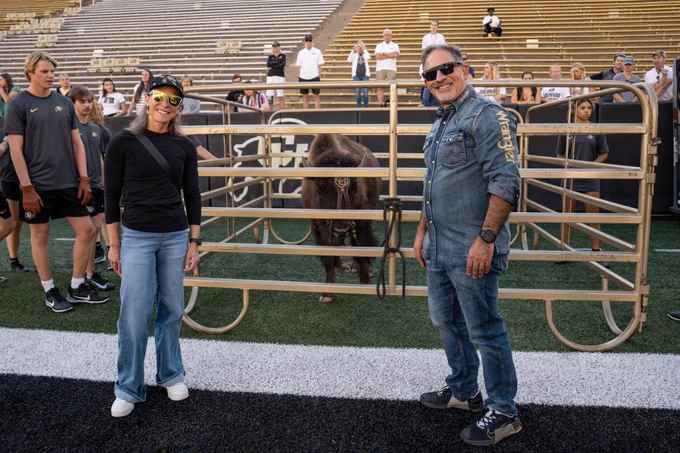Chancellor Schwartz (right) and Dr. LaFrazza (left) smile with Ralphie the Buffalo in her pen in between them. (Credit: University of Colorado)