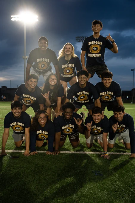 Big Kick Energy players forming a human pyramid, smiling with Champ Shirts on.