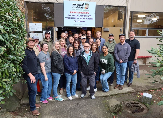 Group of volunteers and staff posing outside Renewal Food Bank under a sign.