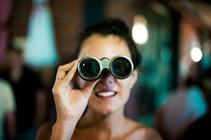 Woman looking through binoculars. Photo by Chase Clark on Unsplash