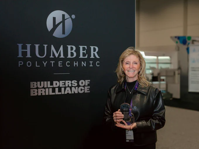 A smiling person is holding an award.